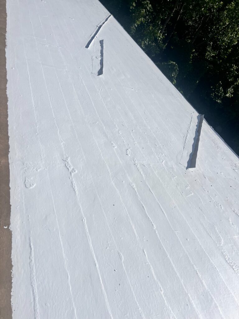 White waterproof roof coating applied to damaged flat roof section